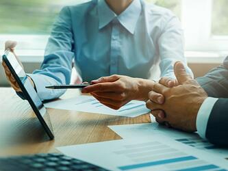 financial advisor consults with client, showing a tablet screen